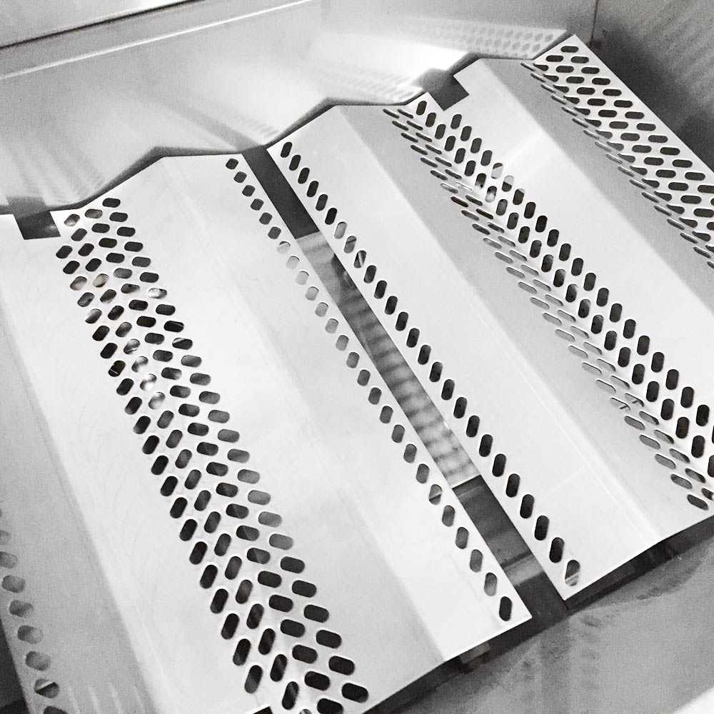 Perforated stainless heat shield plates with raised channels over burner area