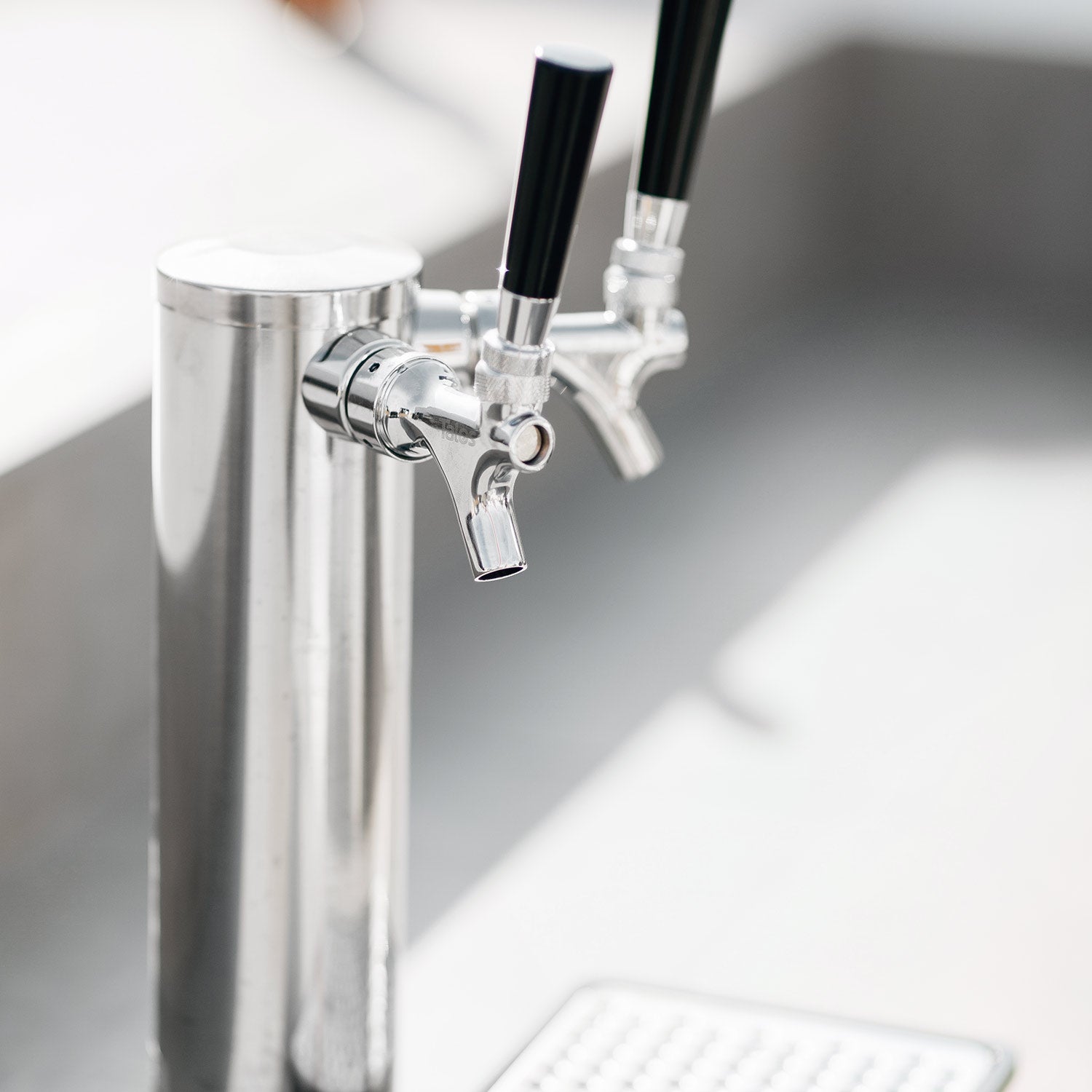 Stainless steel double keg tap with spigot valves and black handle grips