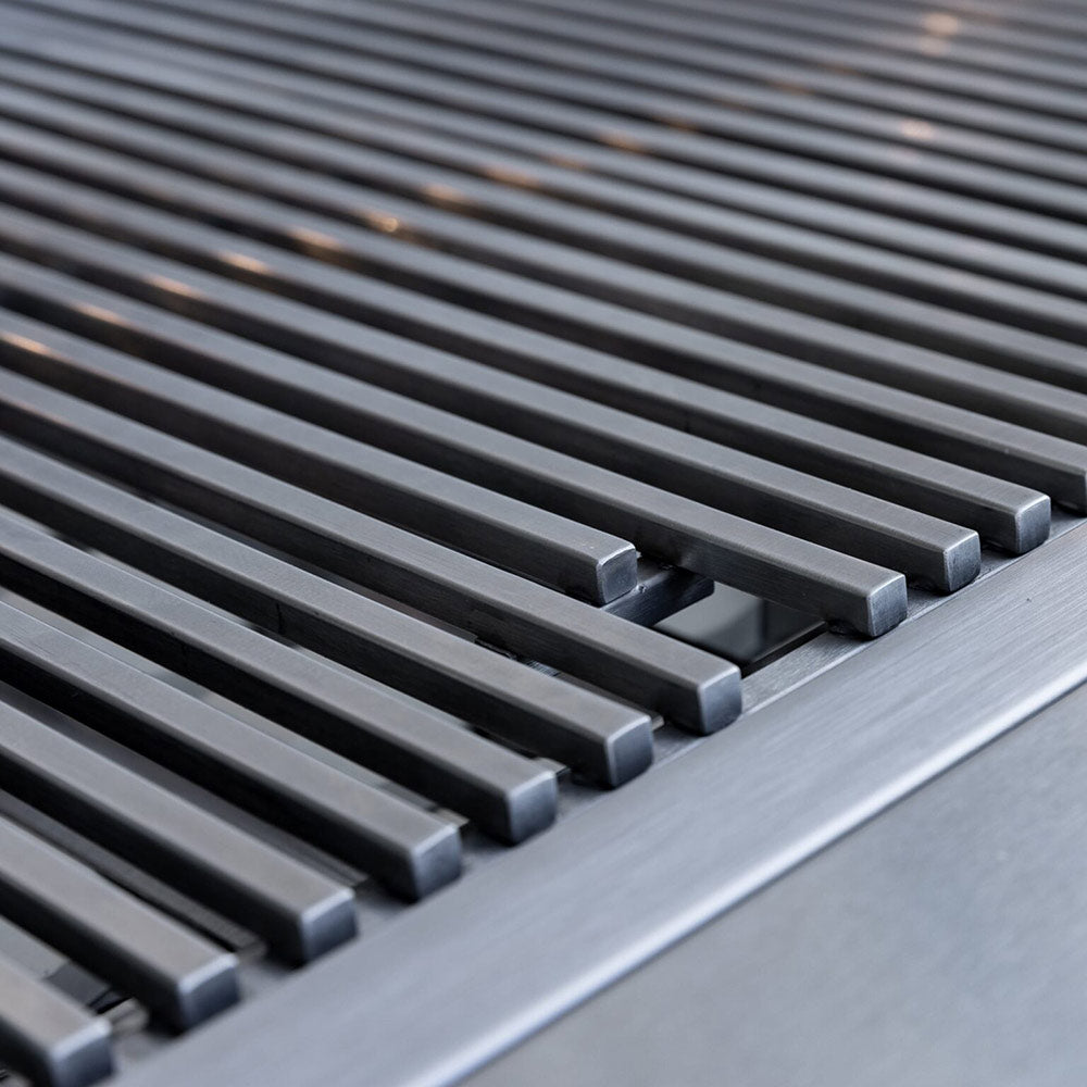 Stainless steel grill grates with evenly spaced bars on a dark cooking surface