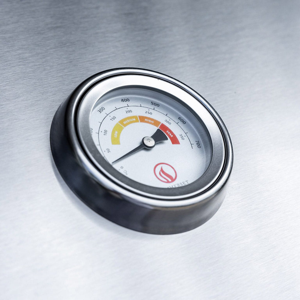 Round temperature gauge with black bezel on the stainless built-in gas grill lid.