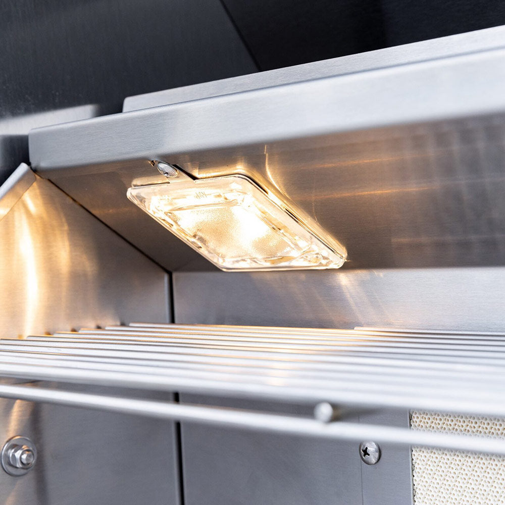 Stainless gas grill interior light under the cooking hood above grates