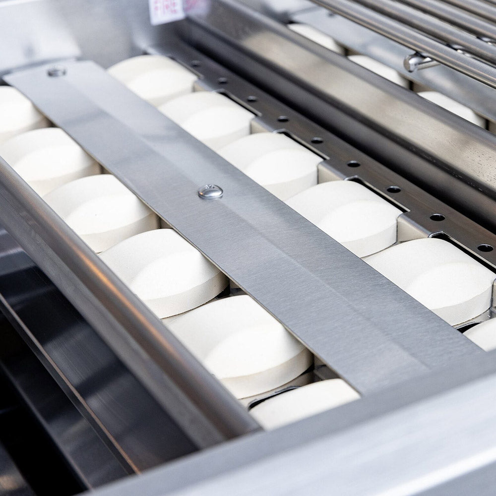 Stainless burner heads beneath the cooking grate bars inside the grill