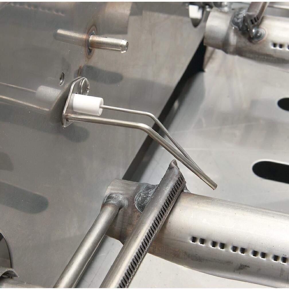Stainless gas valve and tubing connection near the burner area inside the grill.