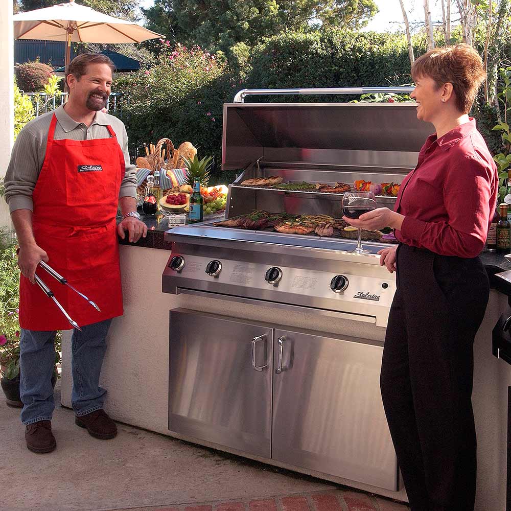 Stainless built-in grill with open hood and front doors, outdoor cooking setup