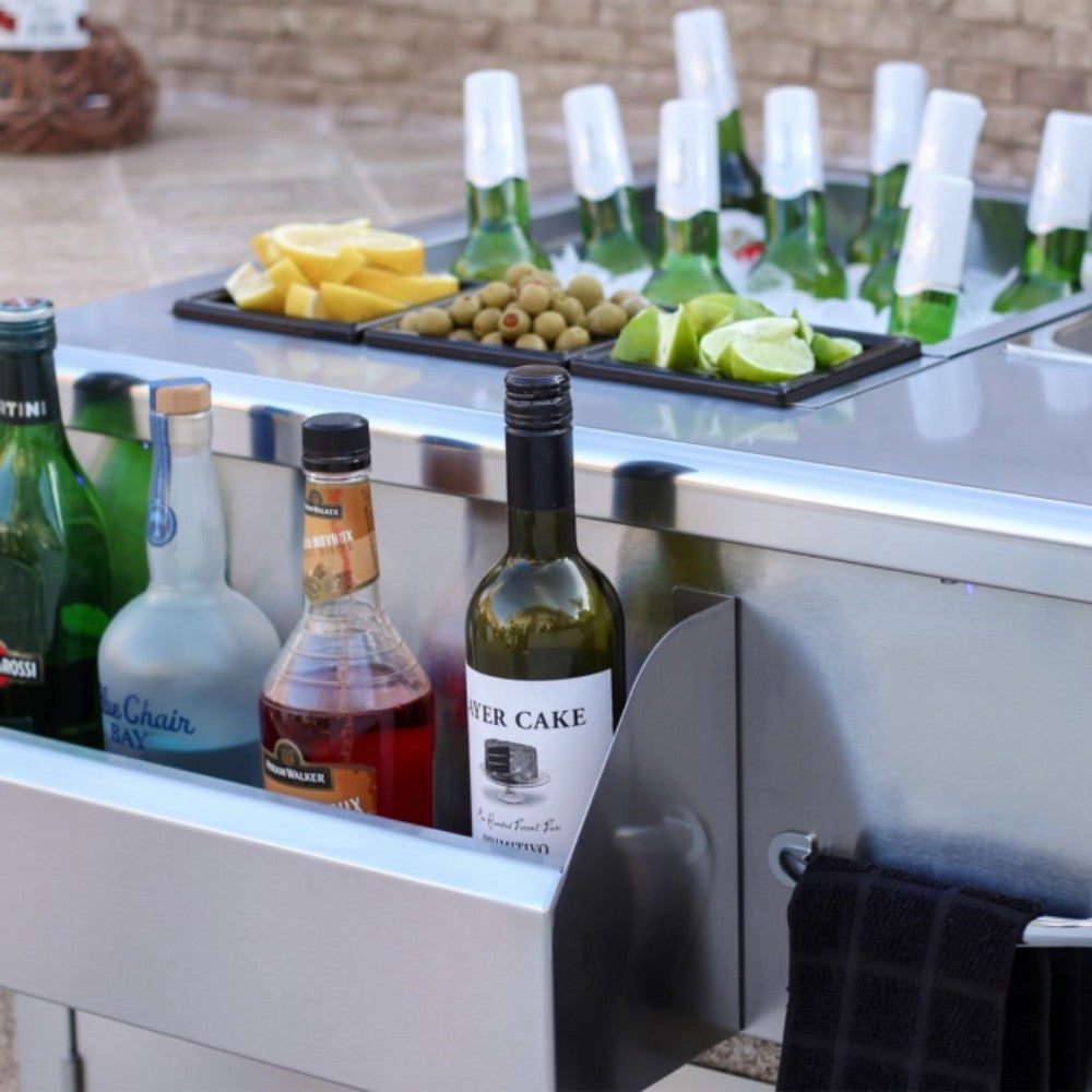 Stainless beverage prep station with open drawer holding bottles and sink basin
