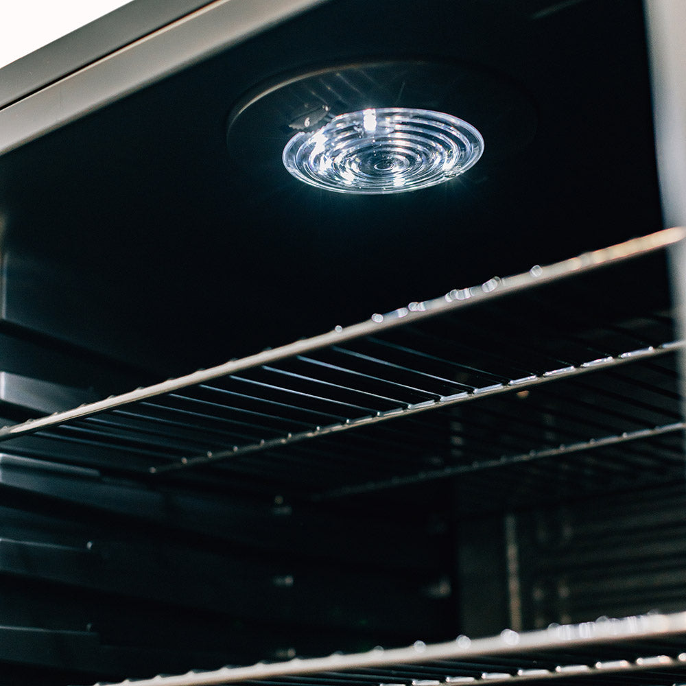Compact refrigerator ceiling light above wire shelves, interior close-up.