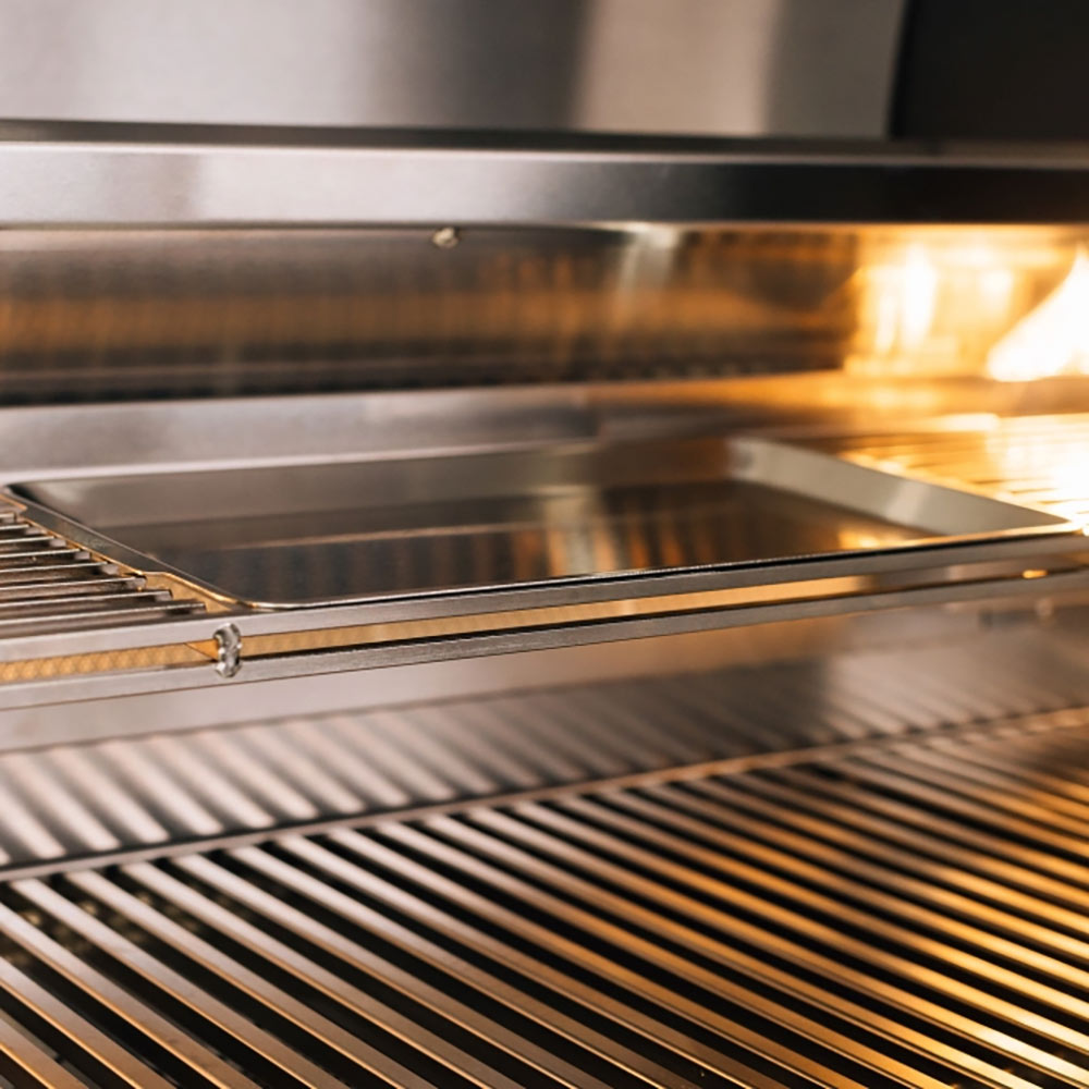 Stainless cooking grates over lit burners inside a built-in gas grill