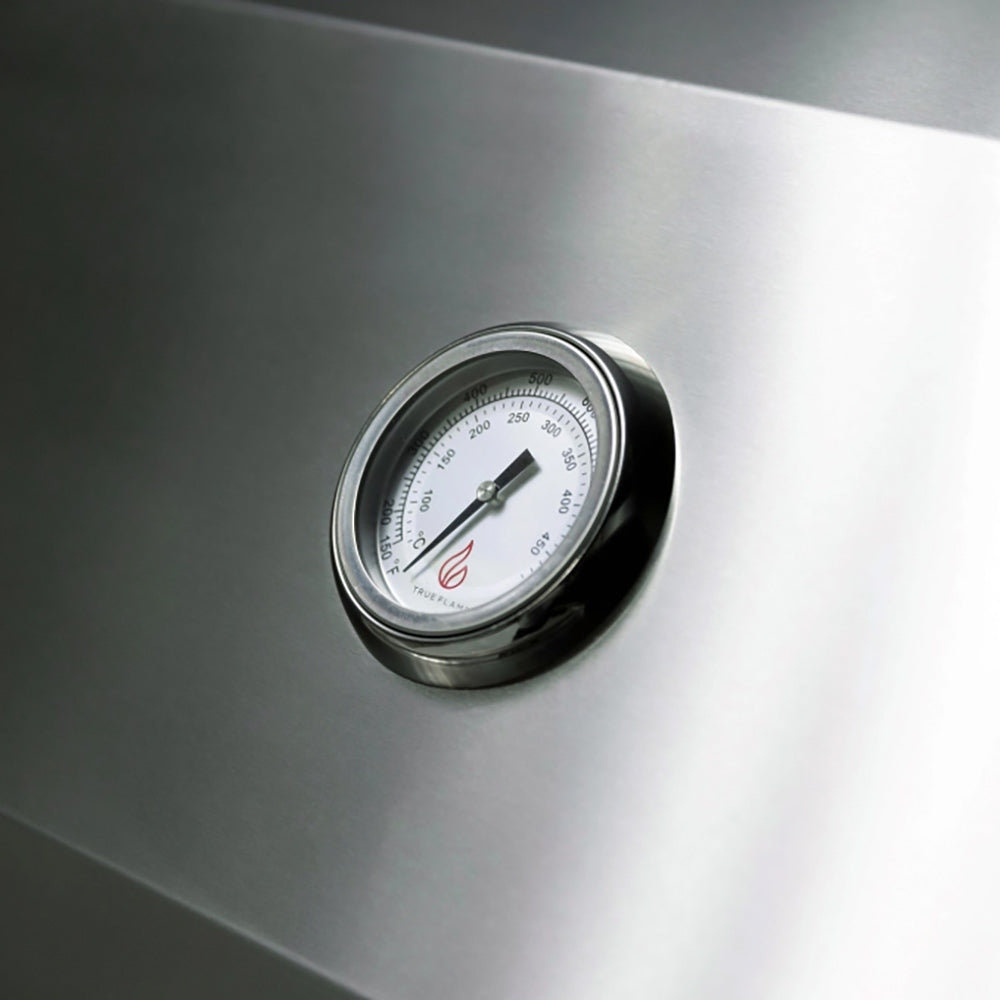 Round stainless grill thermometer with numbered dial on built-in gas grill