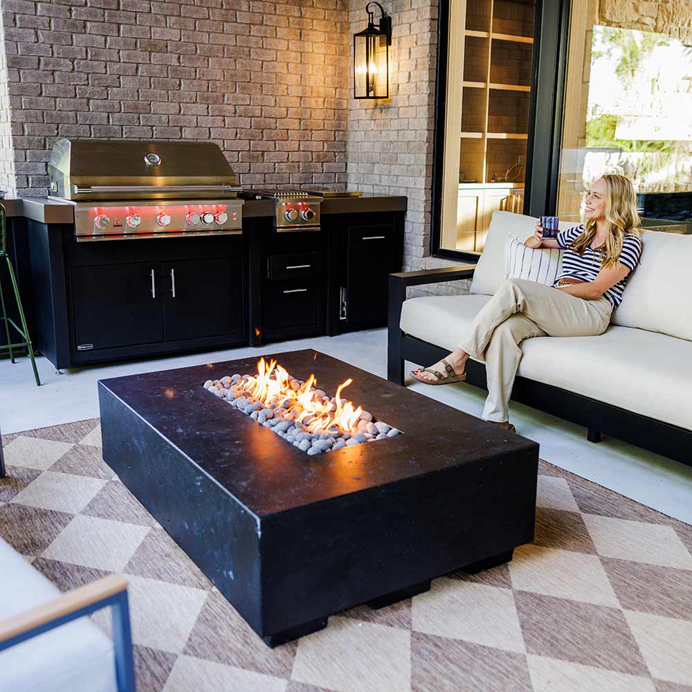 Stainless steel built-in gas grill with control panel and lit burners on patio