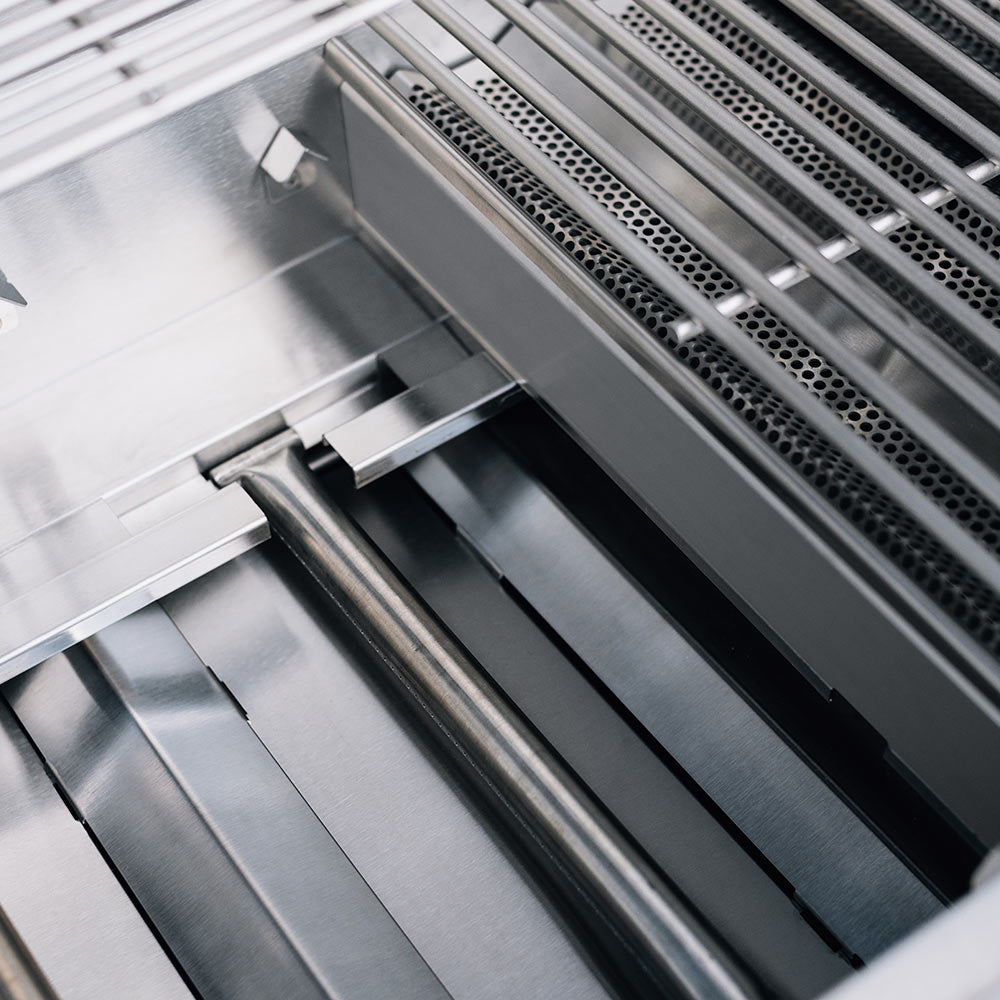 Gas grill firebox interior with burner tubes and metal heat shields