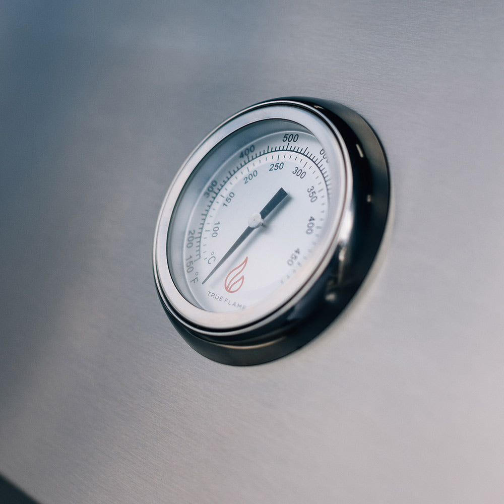 Round temperature gauge on gas grill lid with flame indicator