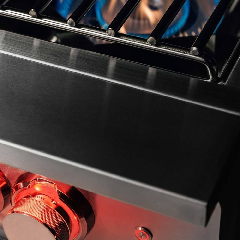 Stainless gas burner control panel with two knobs and red-lit burner area detail.