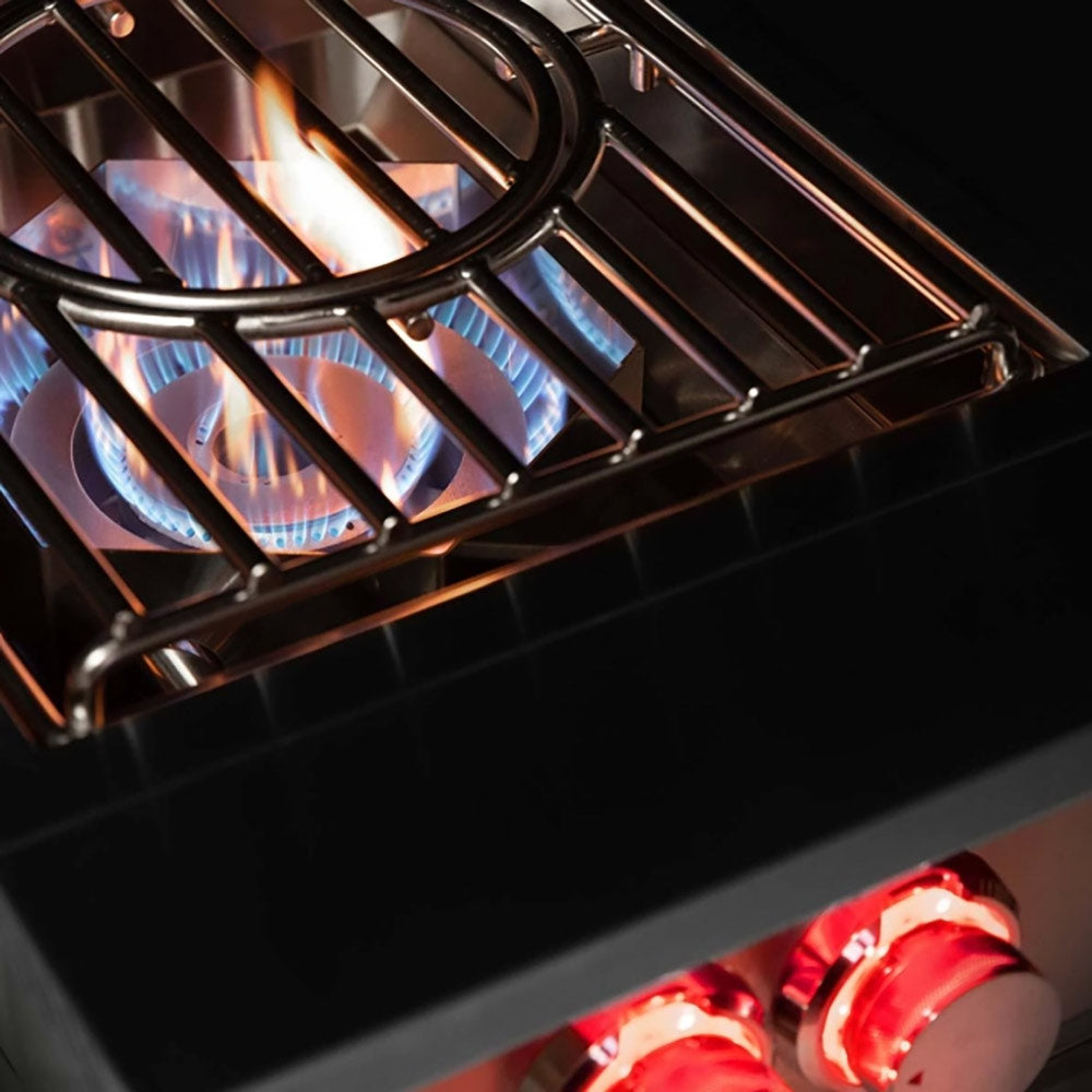 Gas burner with blue flames glowing through black grate and a red control knob.