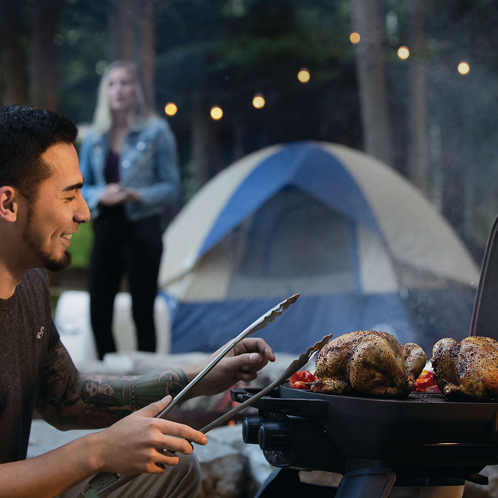 Gas grill with roasted chicken on the grate and lid open