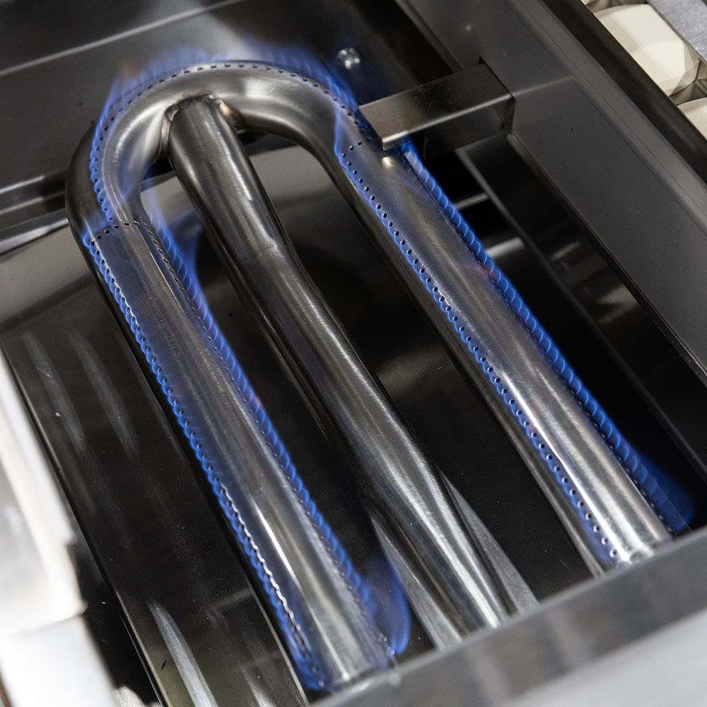 Gas grill burners with blue flames inside the cooking chamber