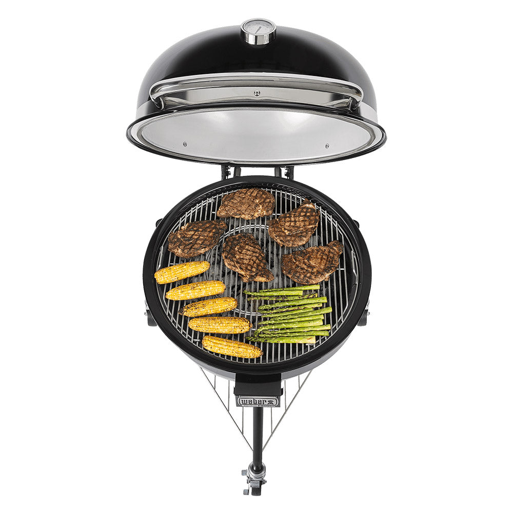 Black kamado grill with lid open, showing grill grates and cooking food over charcoal.