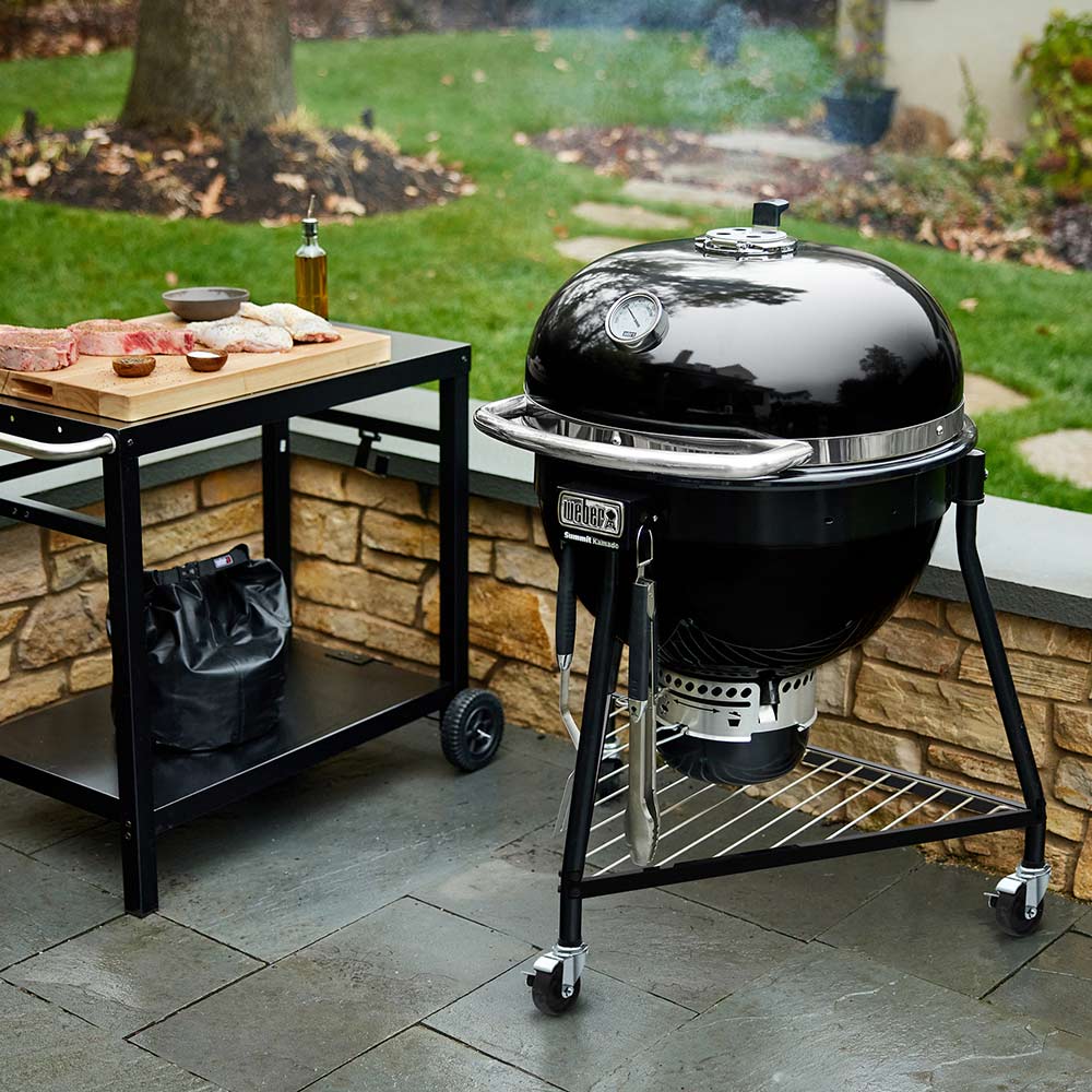 Black kamado charcoal grill with domed lid and side shelf