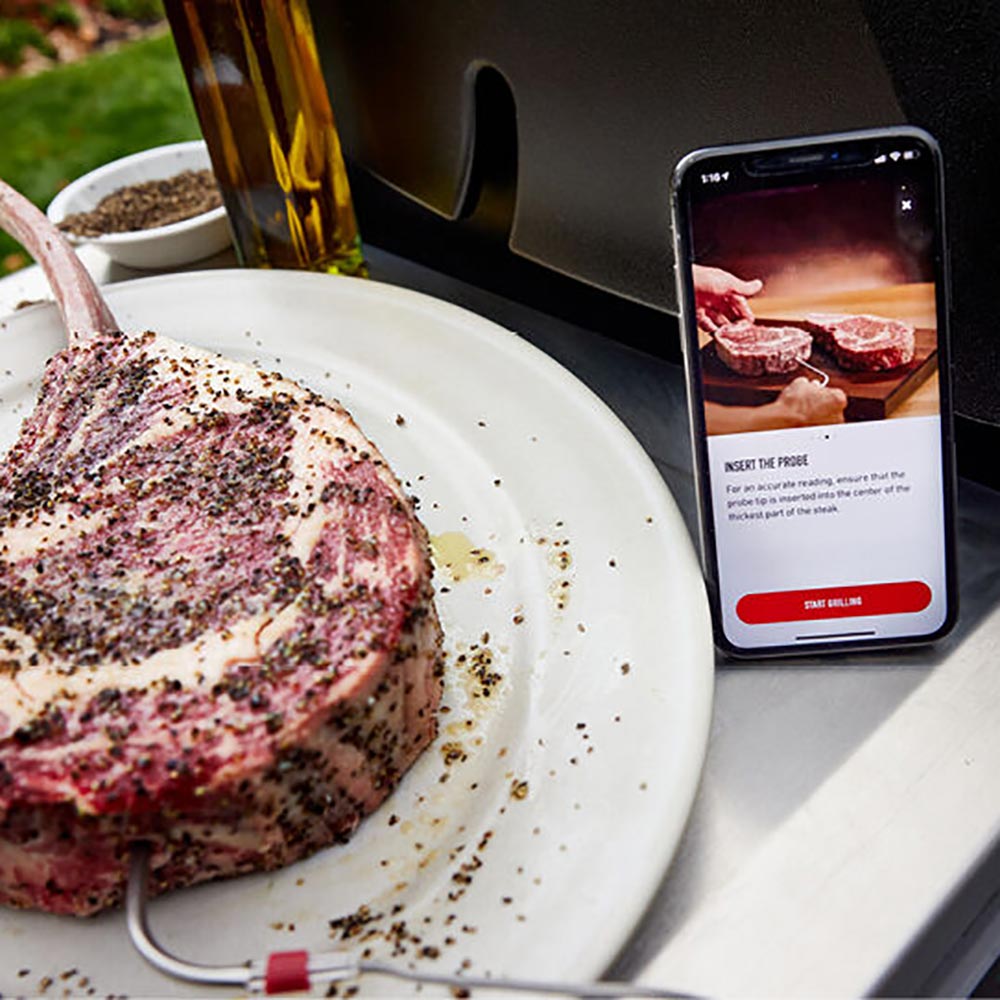 Plate of grilled meat with a smartphone displaying smart grilling instructions