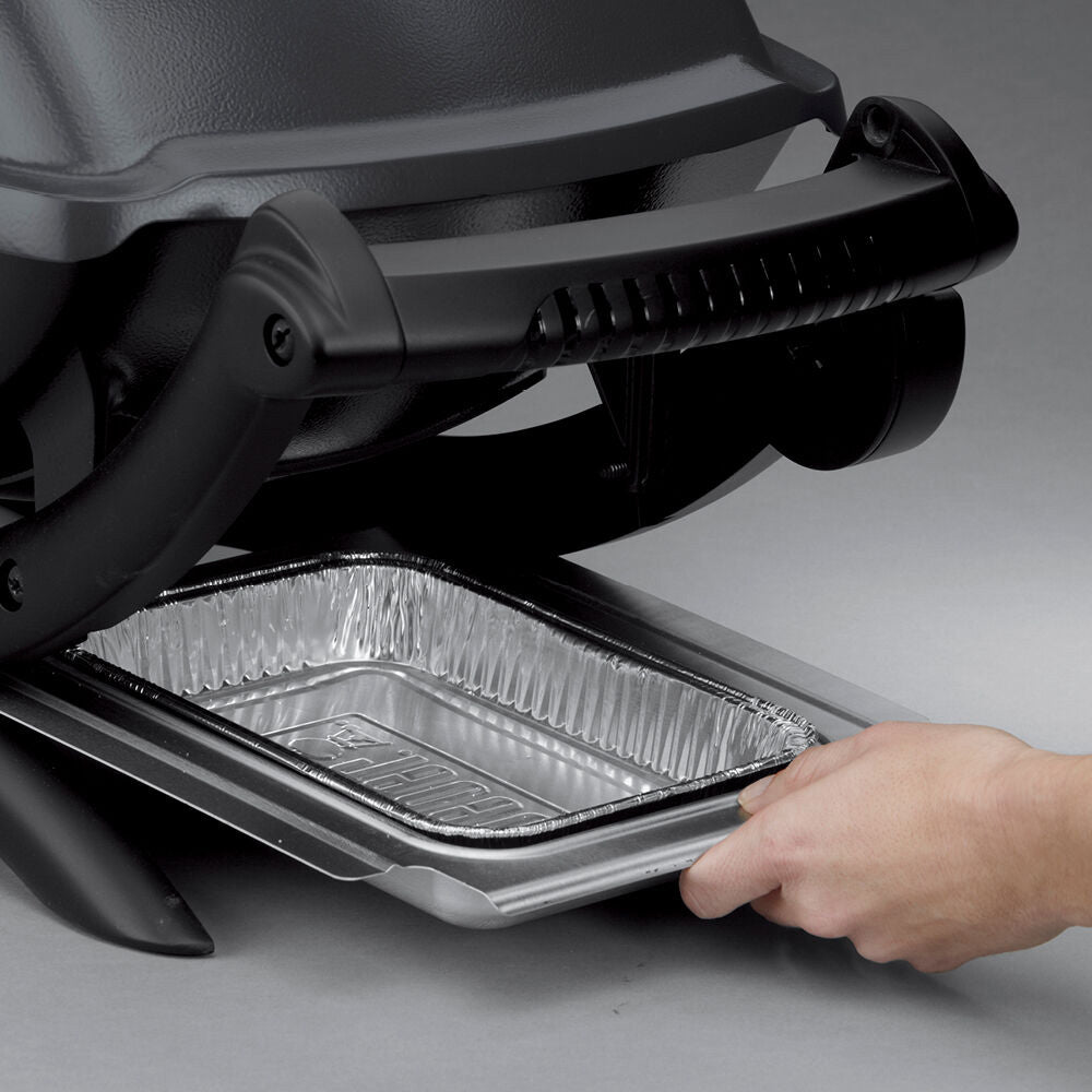 Electric grill open with drip tray extended and hand reaching inside