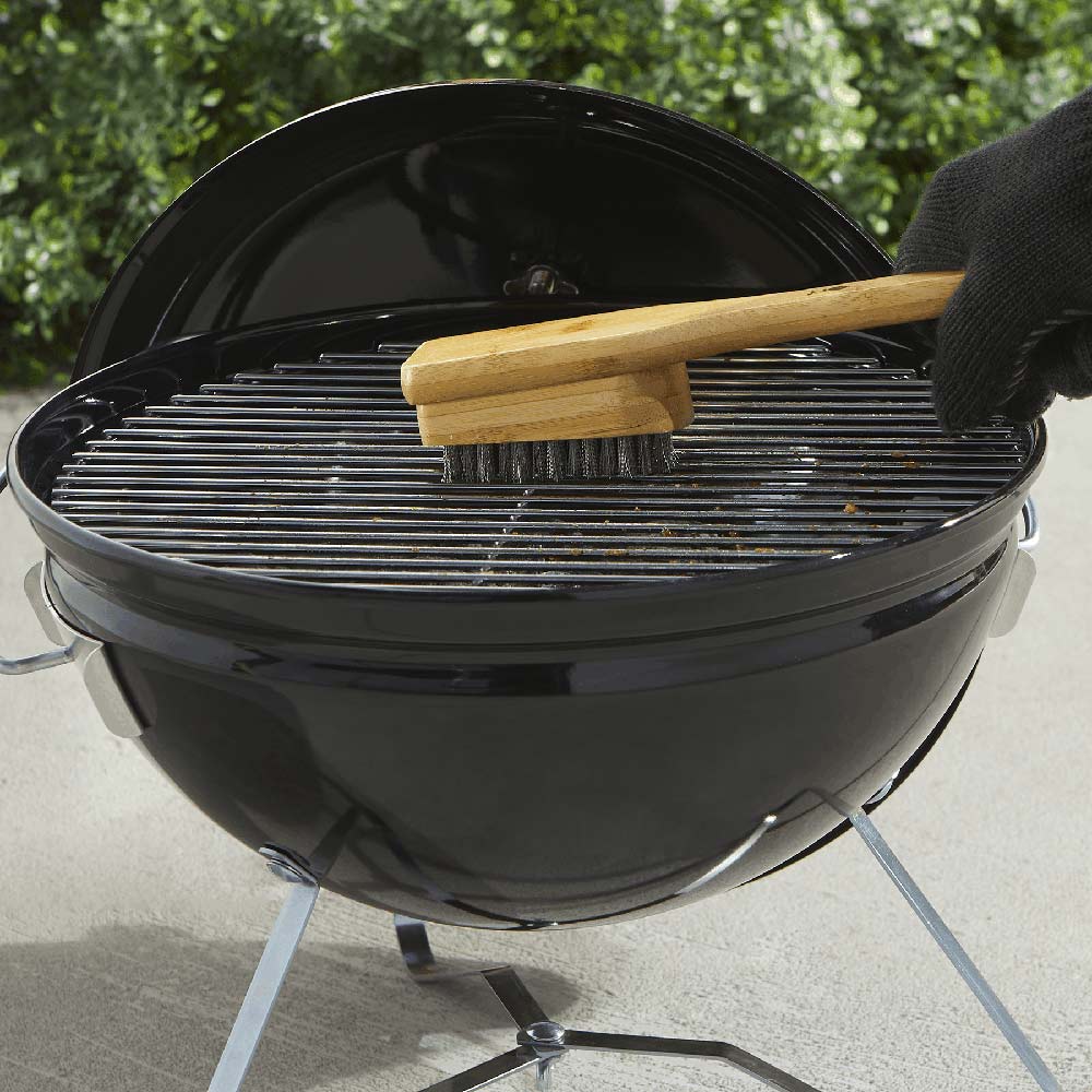 Bamboo grill brush brushing a round charcoal grill grate