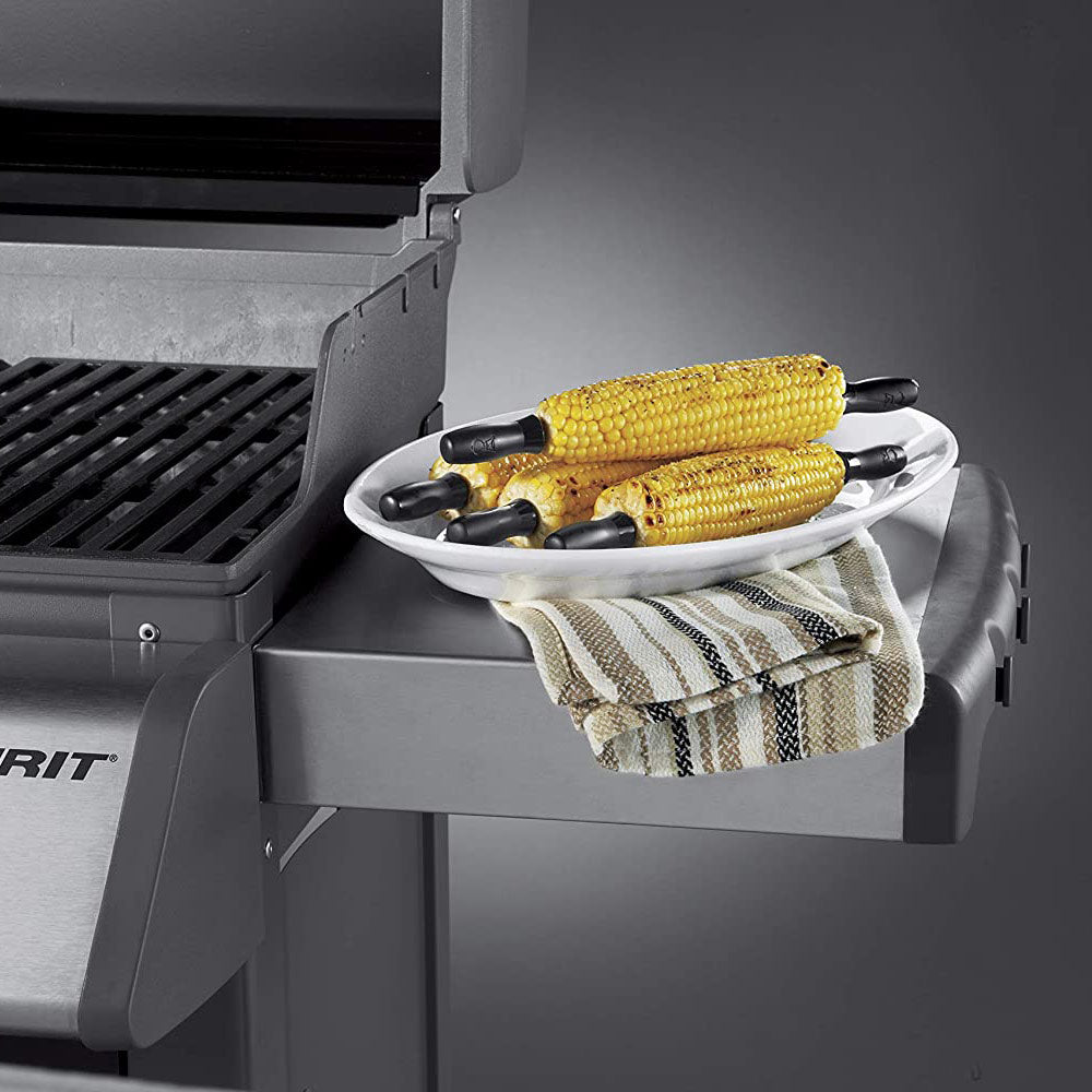 Corn holder set on a grill side tray with two black forks and corn cobs