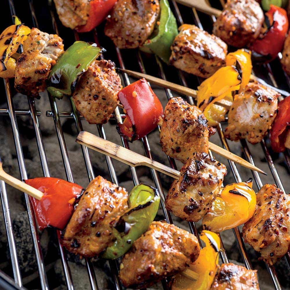 Bamboo skewers with grilled meat and vegetables on a metal grill