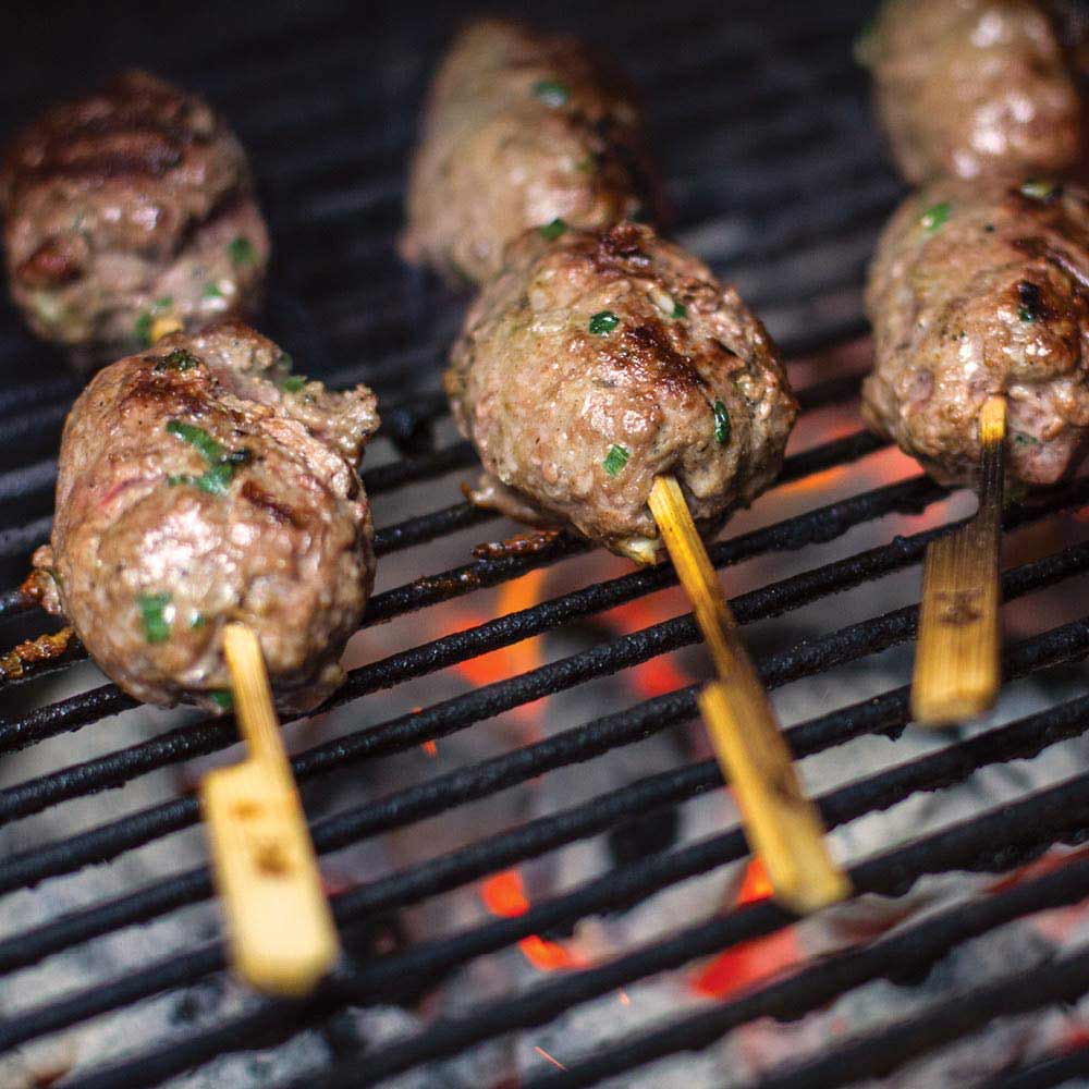 Bamboo skewers holding meat on a wire grill grate
