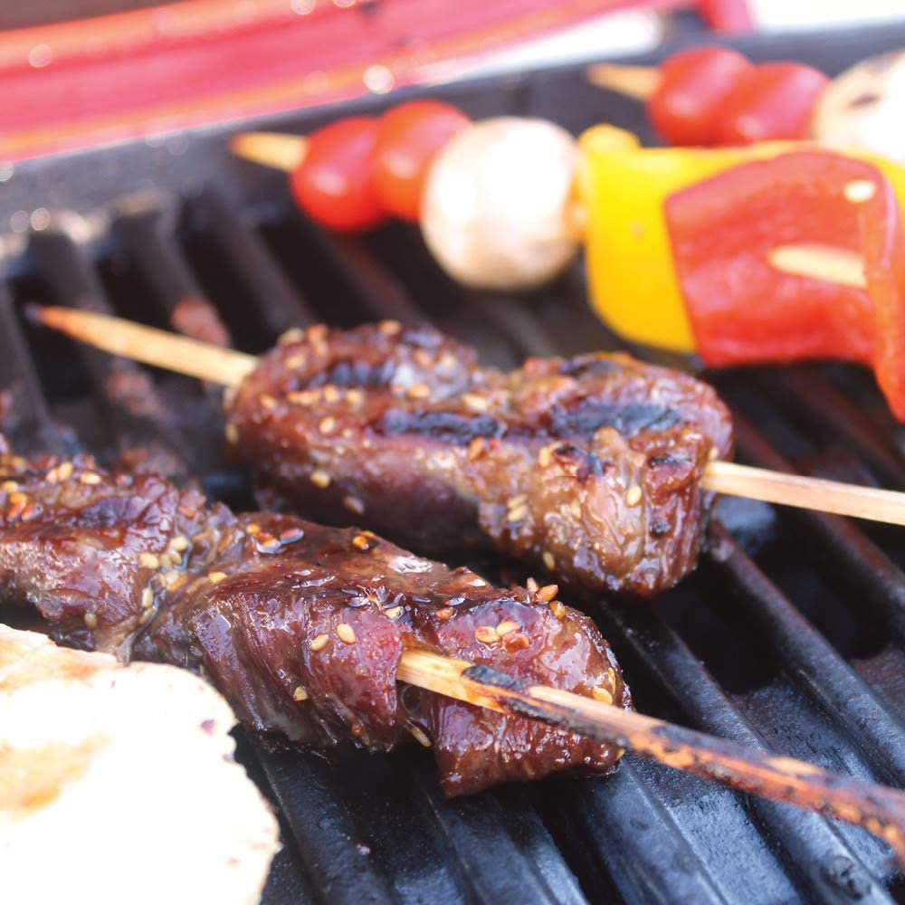 Bamboo skewers with grilled sausage and vegetables on a barbecue grill