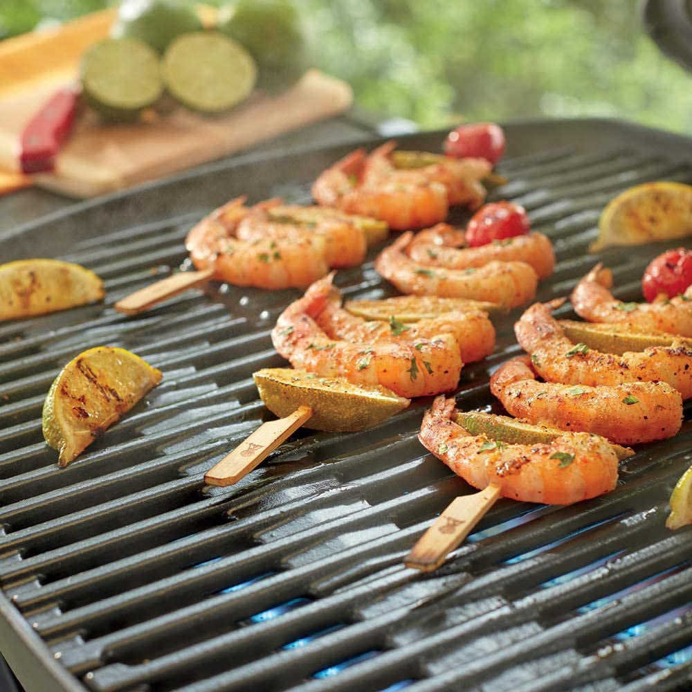 Bamboo skewers with grilled shrimp and lemon slices on a barbecue