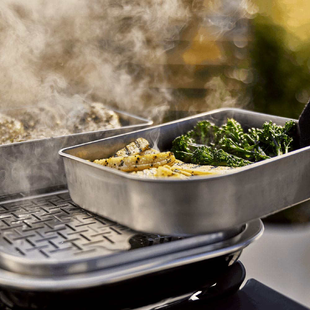 Metal grill expansion tray with broccoli and potatoes, on open grill grate
