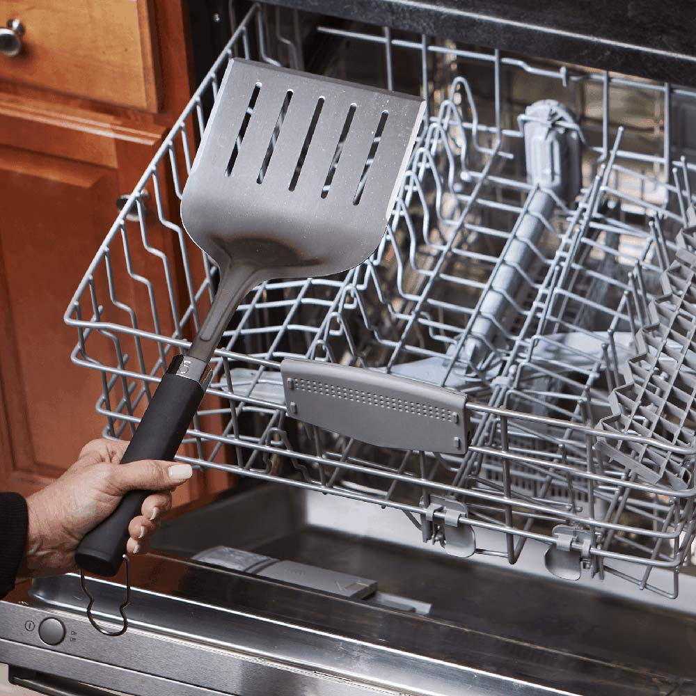 Wide grill spatula in dishwasher rack with black handle and slotted head