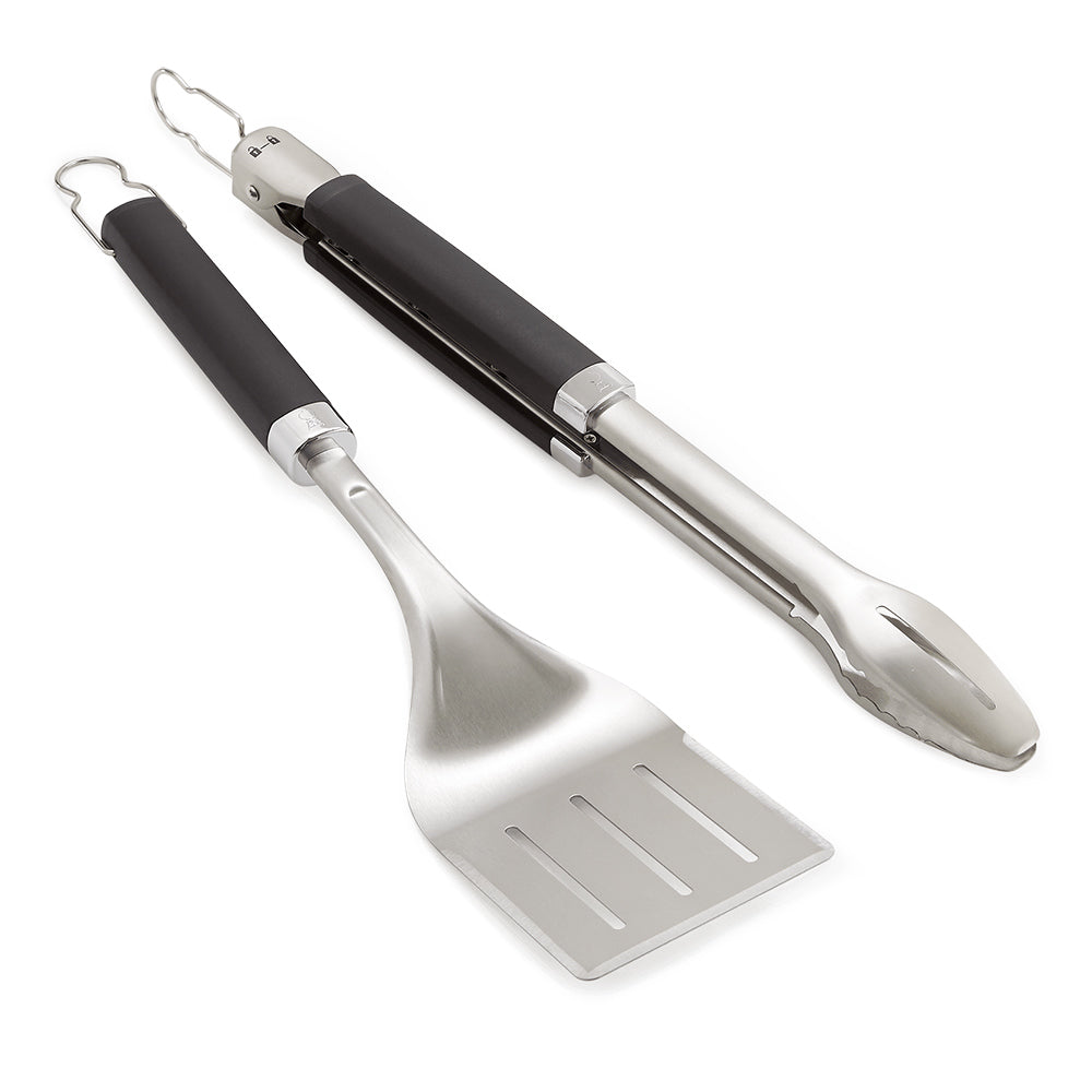 Grill tongs and spatula with black handles and stainless steel heads, angled