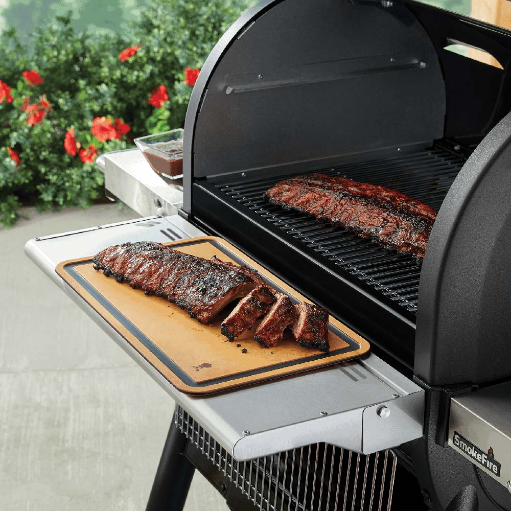 Weber cutting board on grill shelf holding sliced cooked meat