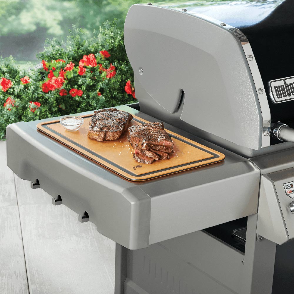 Weber cutting board on grill top with steak slices and small salt cup