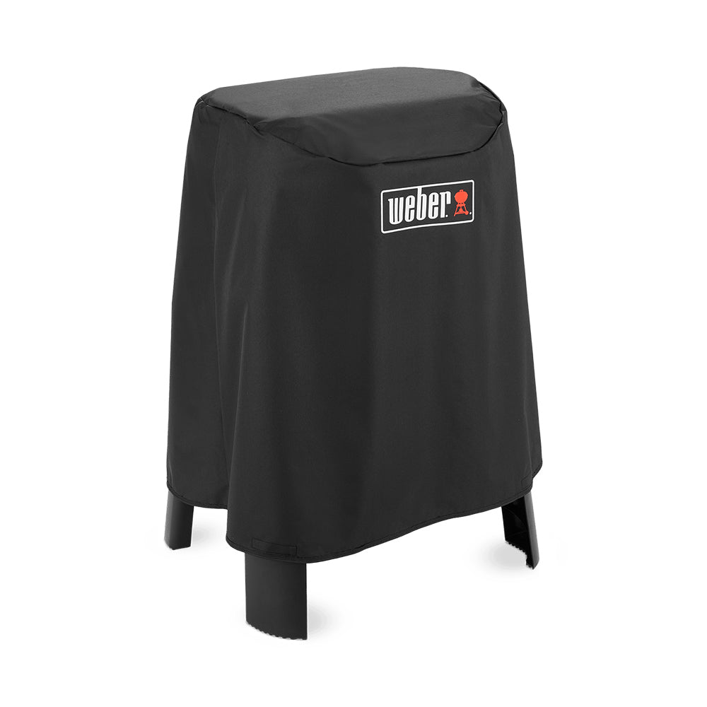 Weber grill cover on stand, dark fabric draped over grill with front logo patch
