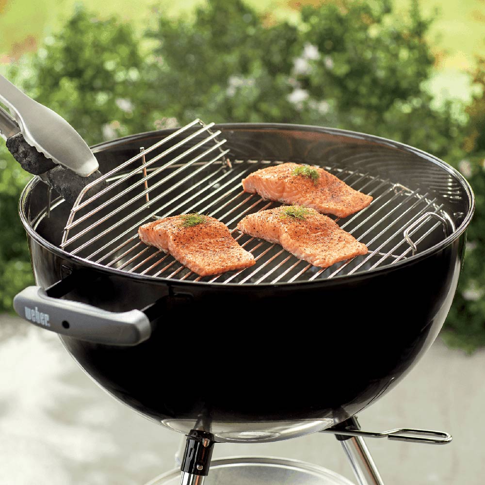 18-inch hinged cooking grate with metal bars on charcoal grill.
