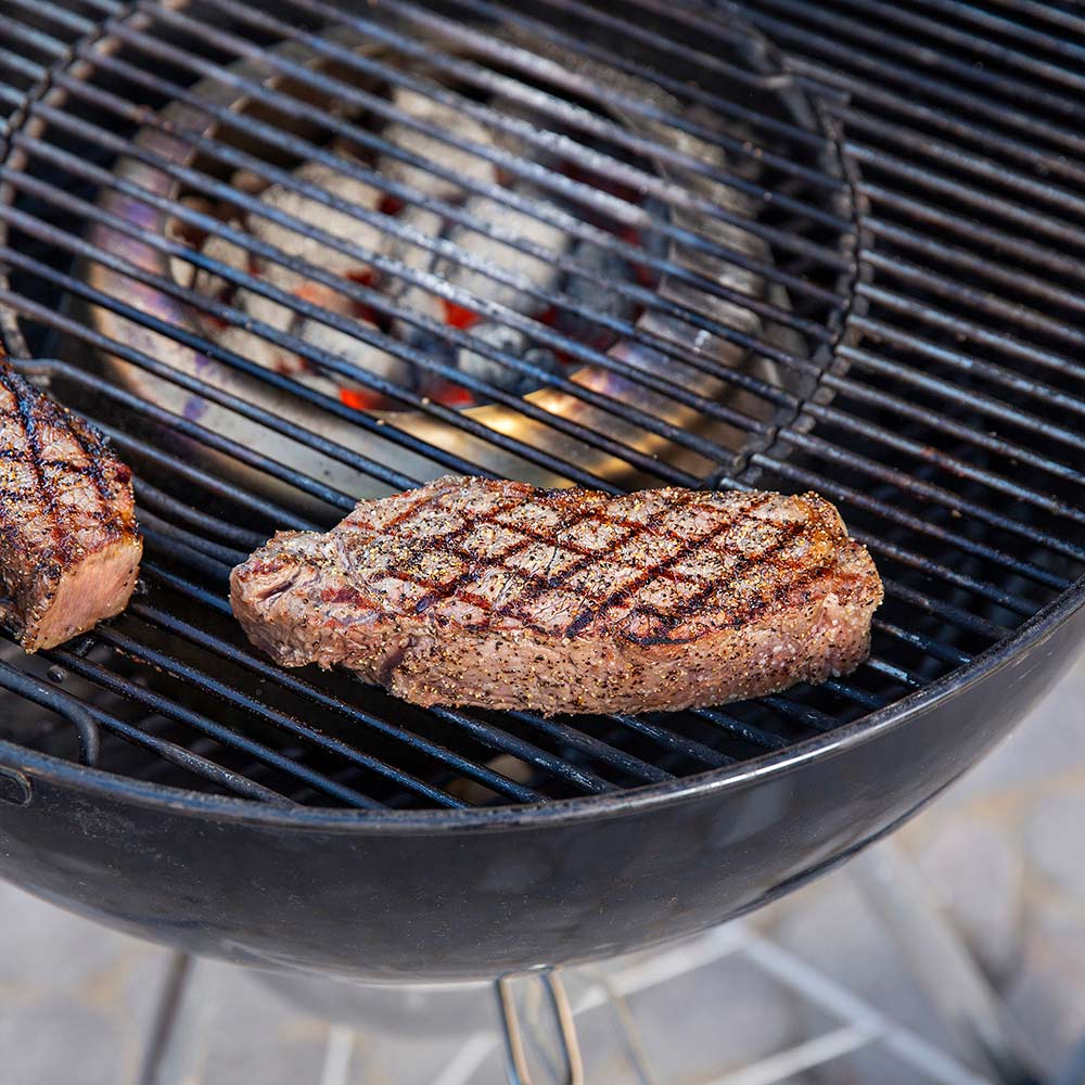 Weber charcoal heat controller, steak on grill grates over glowing charcoal