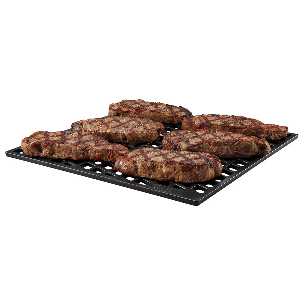 Black dual-sided sear grate with ridged slots, topped with browned meat pieces