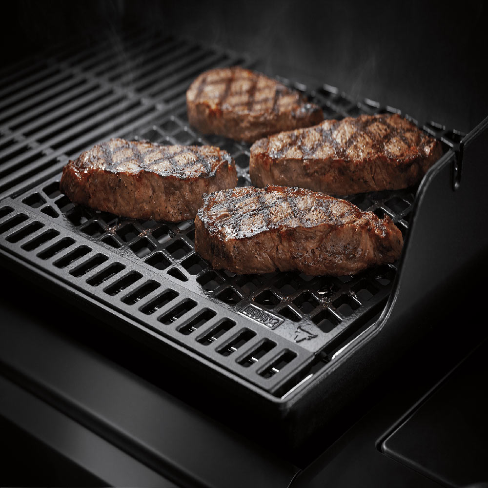 Dual-sided sear grate holding seared steaks, black metal grid on grill