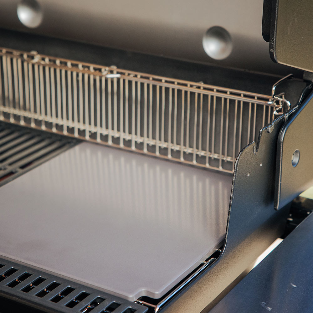 Glazed baking stone set on a grill cooking surface, viewed from above