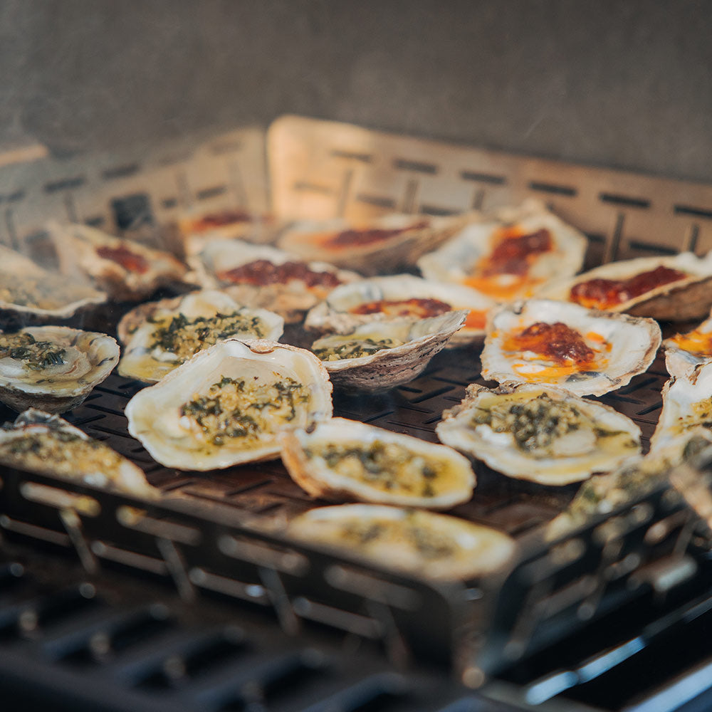 Roasting basket on grill with browned scalloped slices and roasted toppings