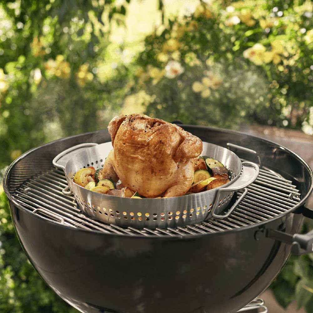 Chicken on a stainless steel roaster basket with perforations on grill grate