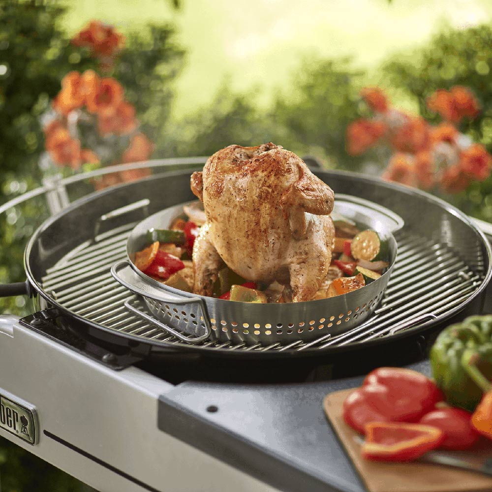 Chicken and mixed vegetables in a stainless steel roaster basket on grill