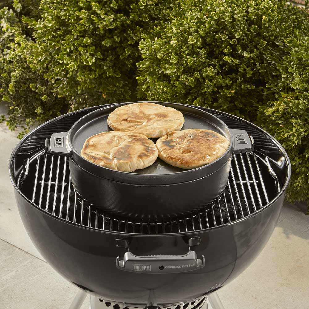 Dutch oven on grill with lid on, holding round flatbread