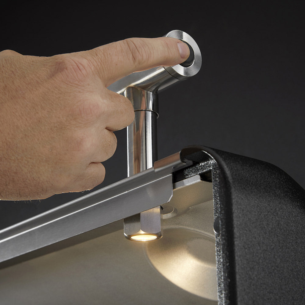 Side burner control knob with lit burner beneath a stainless side shelf