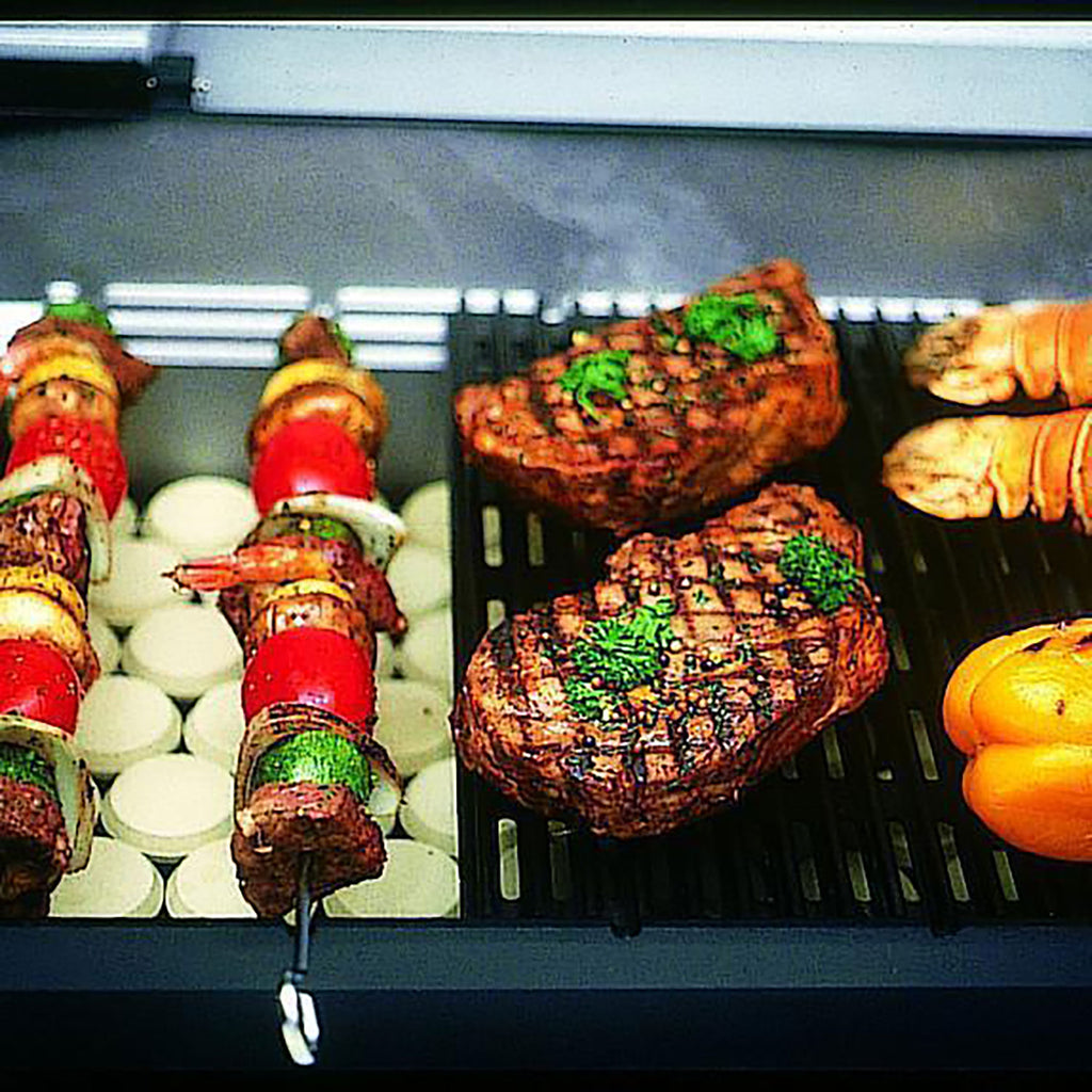 Gas grill grates with grilled skewers, steaks, and sliced vegetables