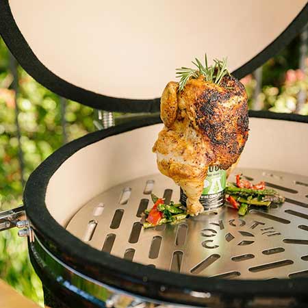 Ceramic asado smoker with open lid showing rotisserie chicken and metal grate