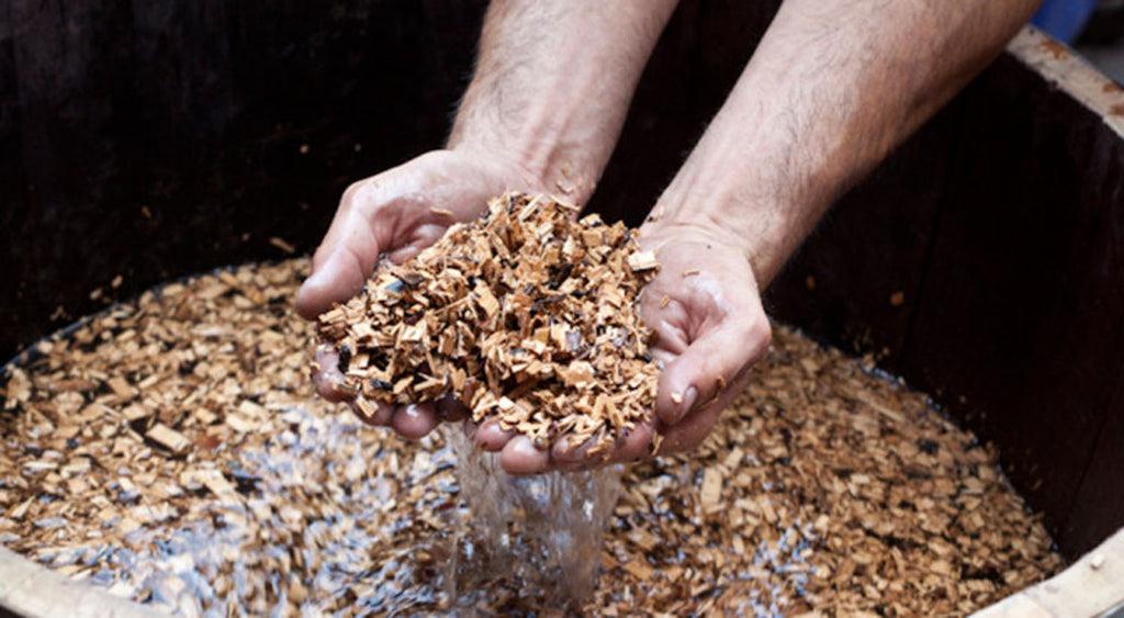 Hands scooping chopped smoking wood chips