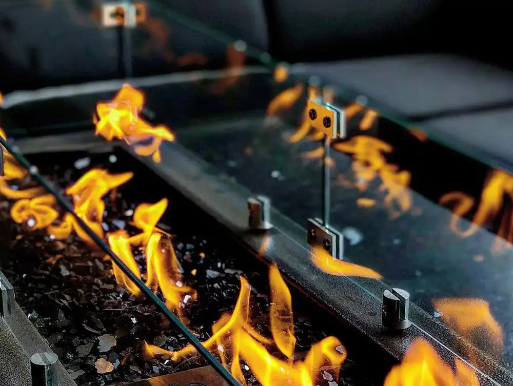 Closeup flame on a linear gas fire pit with reflective wind guard