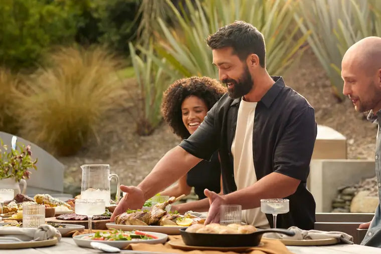 three people enjoying dinner outside during sunset